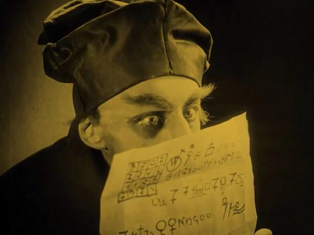 Le comte Orlok jette un regard par-dessus la lettre de Knock, parsemée de symboles cabalistiques